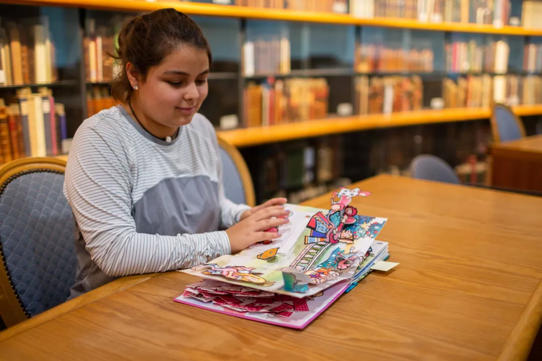 A student looks at a pop-up book