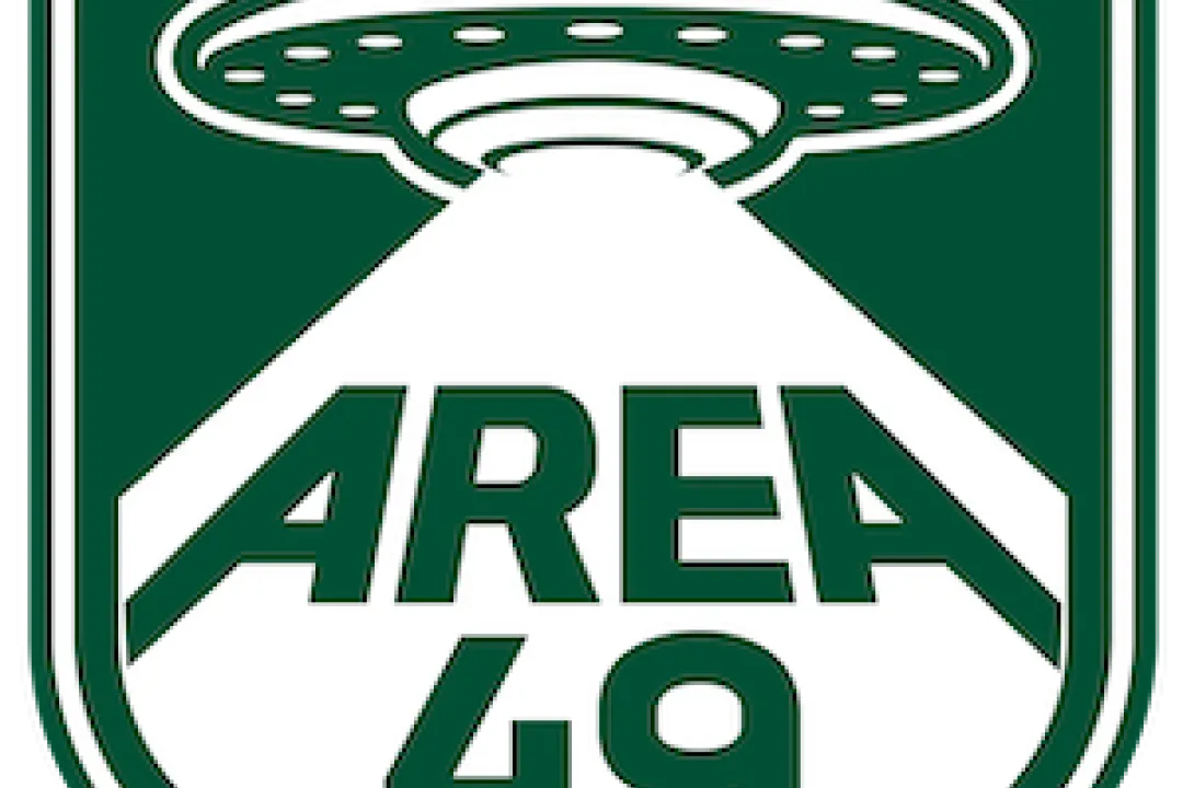 A green and white badge-shaped graphic featuring a UFO abducting the words "Area 49"
